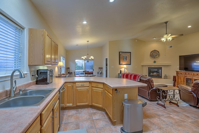 kitchen featuring a glass covered fireplace, open floor plan, a peninsula, vaulted ceiling, and a sink