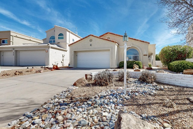 mediterranean / spanish home with an attached garage, a tile roof, concrete driveway, and stucco siding