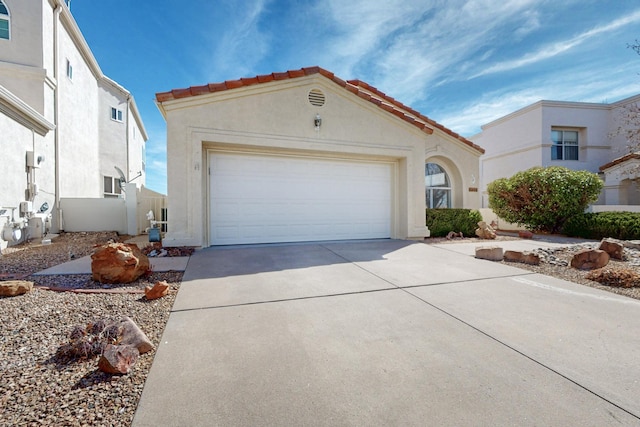 mediterranean / spanish house with a garage, concrete driveway, a tiled roof, and stucco siding