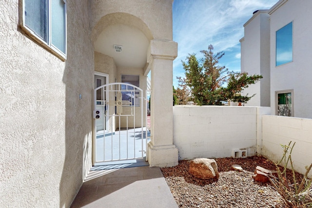 doorway to property featuring fence, a gate, and stucco siding