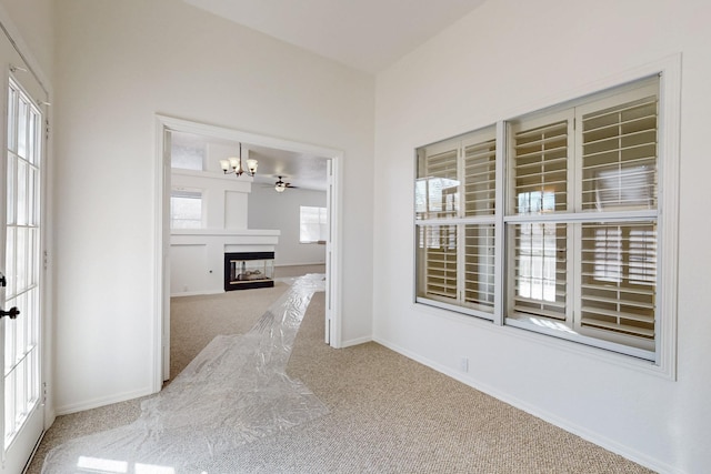 interior space featuring carpet floors, an inviting chandelier, baseboards, and a multi sided fireplace