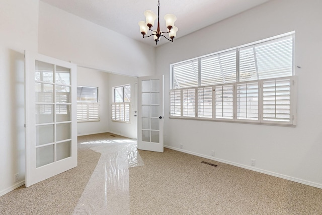 carpeted empty room featuring baseboards, french doors, visible vents, and a notable chandelier