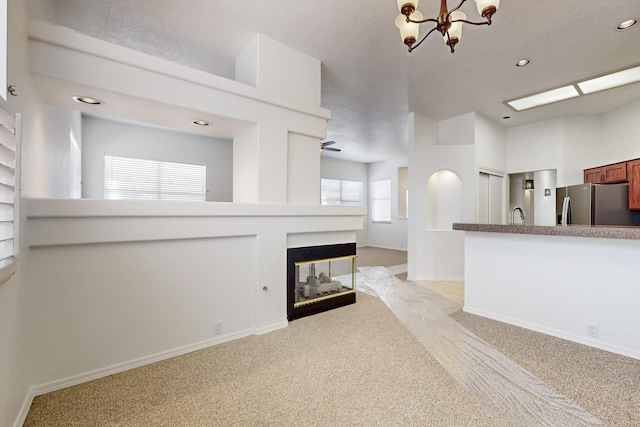 unfurnished living room with recessed lighting, light colored carpet, a multi sided fireplace, a sink, and baseboards