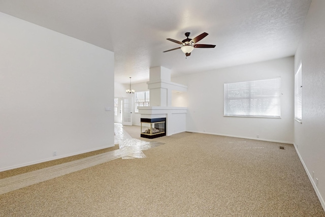 unfurnished living room featuring baseboards, light colored carpet, a multi sided fireplace, and ceiling fan with notable chandelier