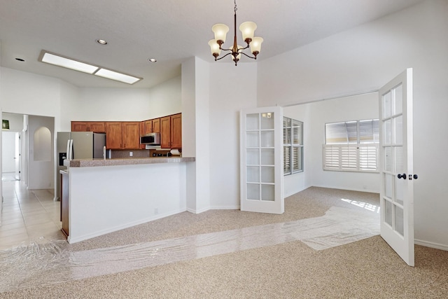 kitchen with decorative light fixtures, stainless steel appliances, a high ceiling, brown cabinetry, and open floor plan