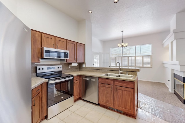 kitchen with a peninsula, brown cabinetry, stainless steel appliances, and a sink