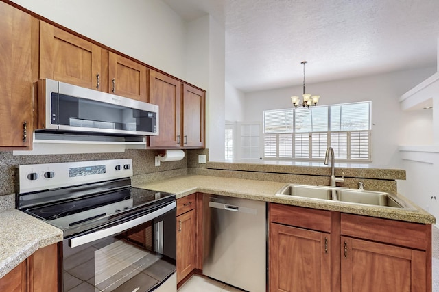 kitchen with appliances with stainless steel finishes, decorative backsplash, a sink, and brown cabinets