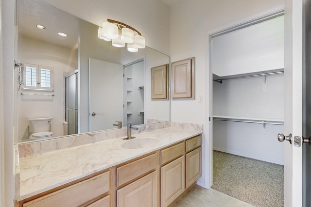 bathroom with a walk in closet, a shower with door, toilet, vanity, and baseboards