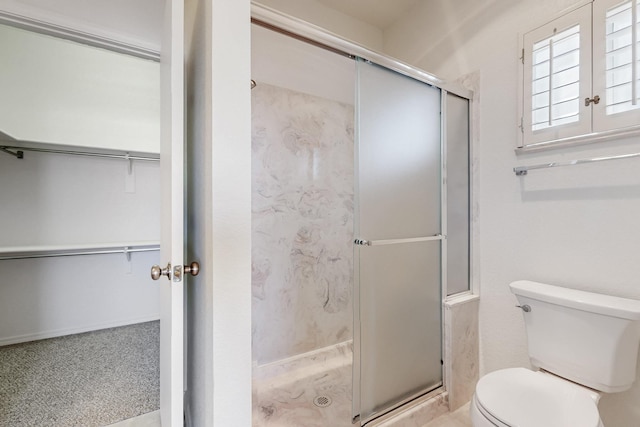 bathroom featuring a shower stall, toilet, and a walk in closet