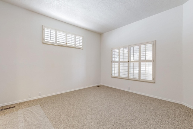 carpeted spare room featuring baseboards, visible vents, and a textured ceiling