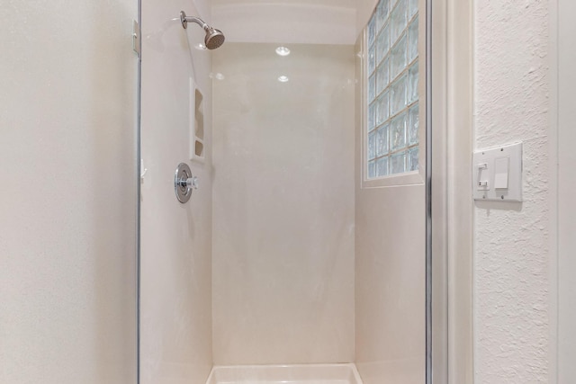 bathroom with a stall shower and a textured wall