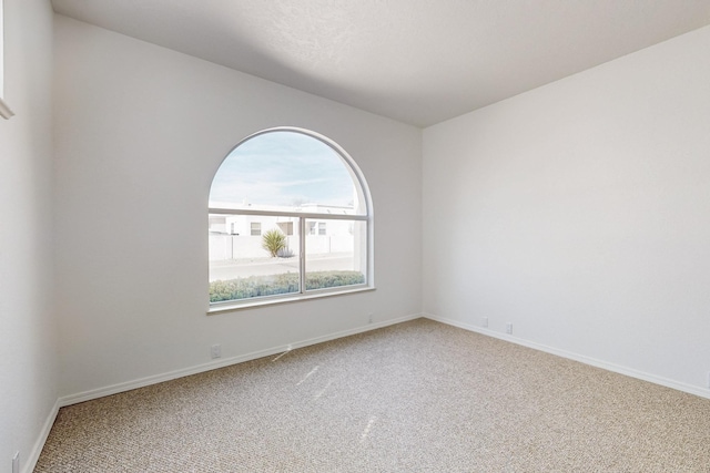 carpeted spare room featuring baseboards