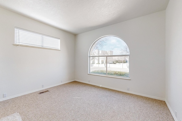 spare room with a textured ceiling, plenty of natural light, visible vents, and baseboards