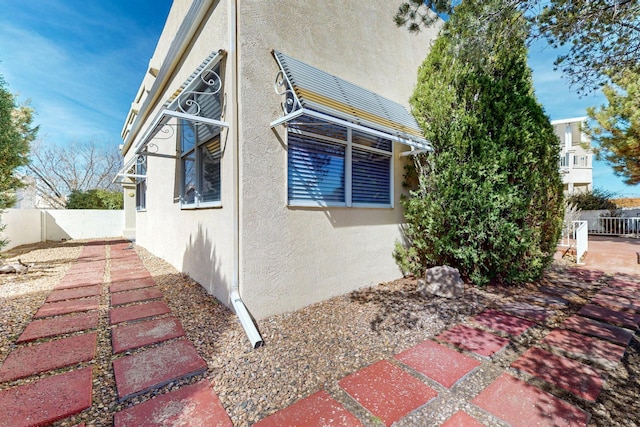 view of property exterior with fence and stucco siding