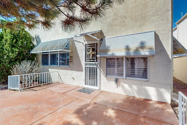 back of property featuring a patio and stucco siding