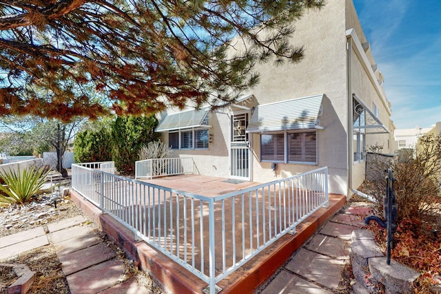 rear view of property with fence and stucco siding