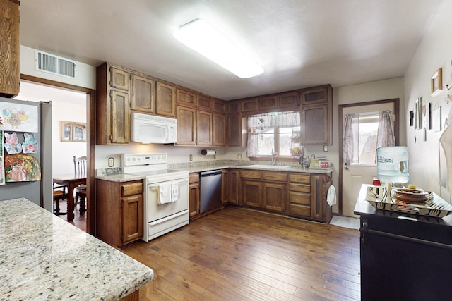 kitchen with stainless steel appliances, dark wood-style flooring, a sink, visible vents, and brown cabinetry