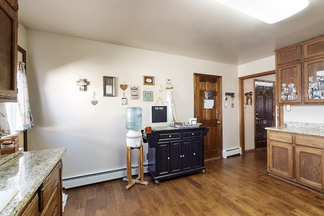 kitchen featuring light stone counters, baseboard heating, dark wood finished floors, and brown cabinetry