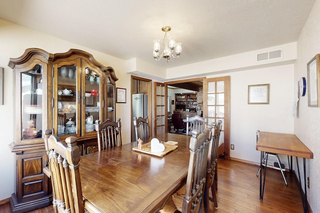 dining room with baseboards, visible vents, hardwood / wood-style flooring, french doors, and a notable chandelier