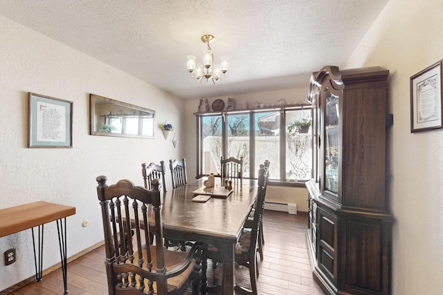 dining room featuring a baseboard heating unit, a textured ceiling, hardwood / wood-style flooring, and an inviting chandelier