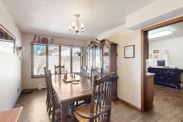 dining area featuring baseboards, dark wood finished floors, a baseboard radiator, a textured ceiling, and a chandelier