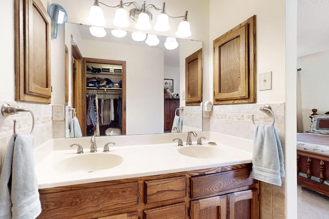 ensuite bathroom with double vanity, connected bathroom, a walk in closet, and a sink