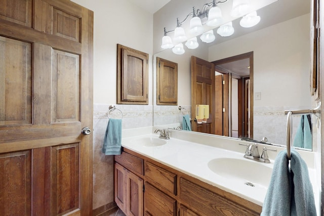 full bathroom with double vanity, tile walls, a sink, and wainscoting