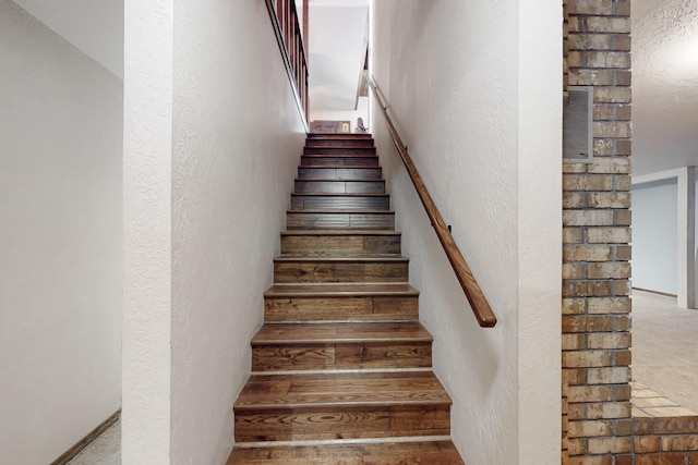 staircase featuring a textured wall