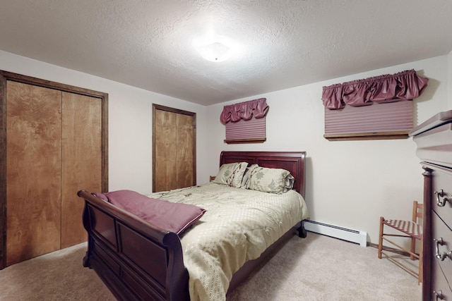 bedroom featuring a baseboard heating unit, carpet floors, and a textured ceiling