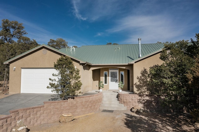 single story home with a garage, metal roof, driveway, and stucco siding