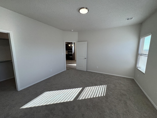 unfurnished bedroom with a textured ceiling, visible vents, and carpet