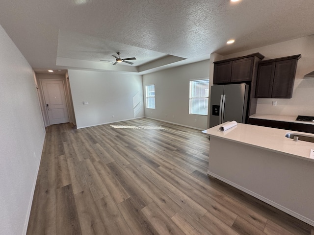 kitchen featuring a textured ceiling, a tray ceiling, wood finished floors, and stainless steel fridge with ice dispenser