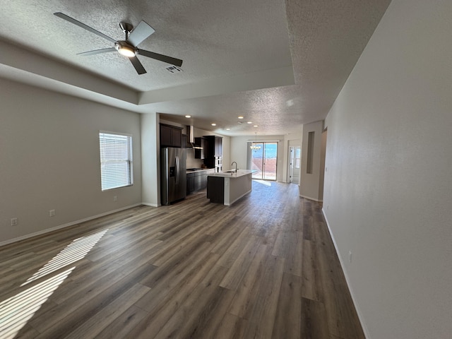 unfurnished living room with visible vents, ceiling fan, a textured ceiling, and dark wood-type flooring
