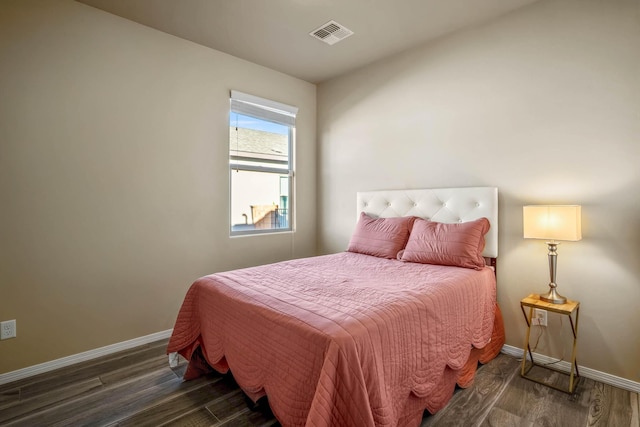 bedroom with wood finished floors, visible vents, and baseboards