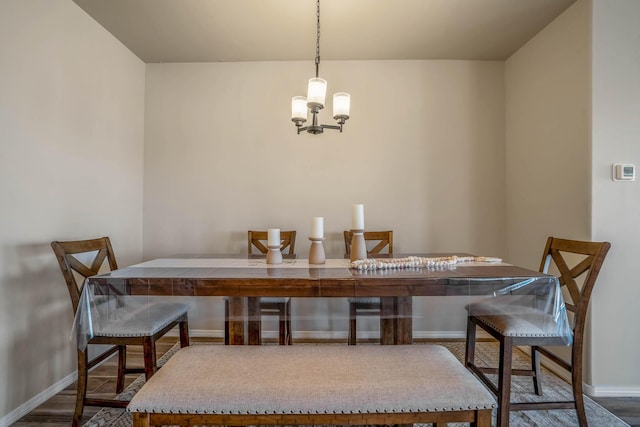 dining room with a notable chandelier, baseboards, and wood finished floors