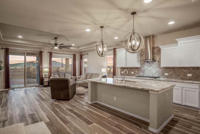 kitchen with dark wood finished floors, stainless steel gas stovetop, wall chimney exhaust hood, and a sink