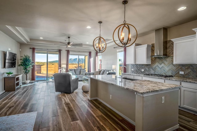 kitchen featuring a sink, wall chimney exhaust hood, dark wood-style flooring, and stainless steel gas cooktop