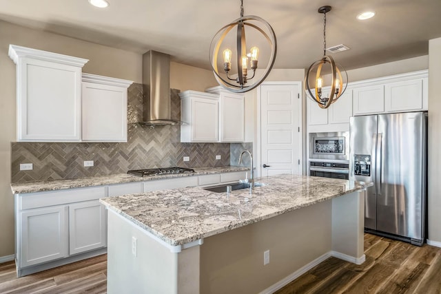 kitchen with dark wood-style flooring, stainless steel appliances, wall chimney exhaust hood, and a sink