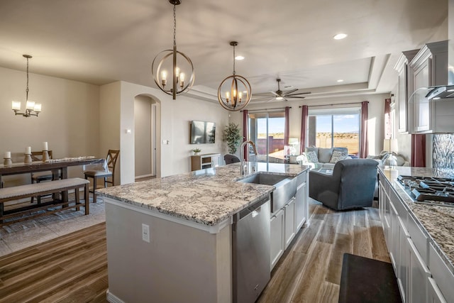 kitchen with arched walkways, dark wood-style flooring, a sink, stainless steel appliances, and open floor plan