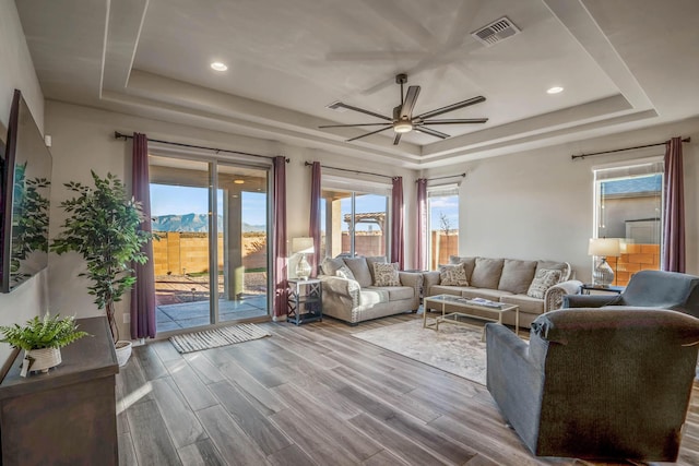 living area featuring visible vents, a tray ceiling, and wood finished floors