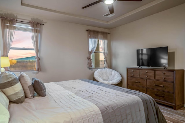 bedroom featuring visible vents, multiple windows, and a raised ceiling