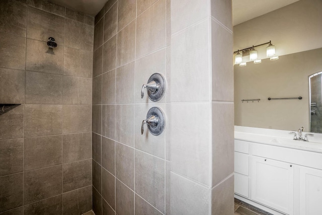 full bath with a tile shower and vanity