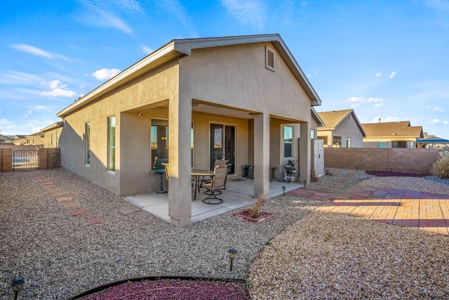 back of house with stucco siding, a patio, and a fenced backyard