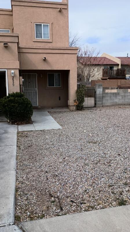 exterior space featuring stucco siding, fence, and a gate