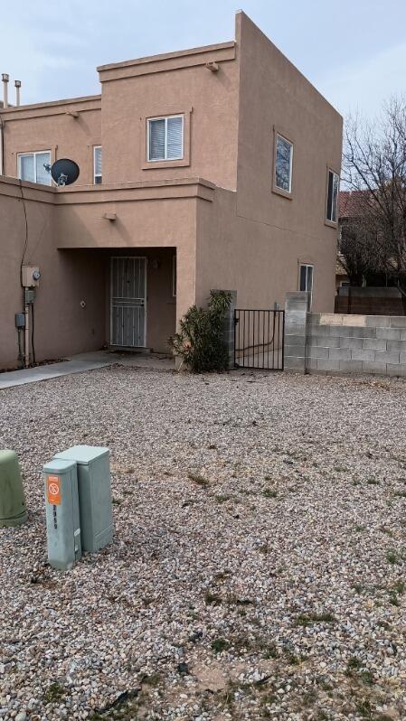 rear view of property with stucco siding and fence