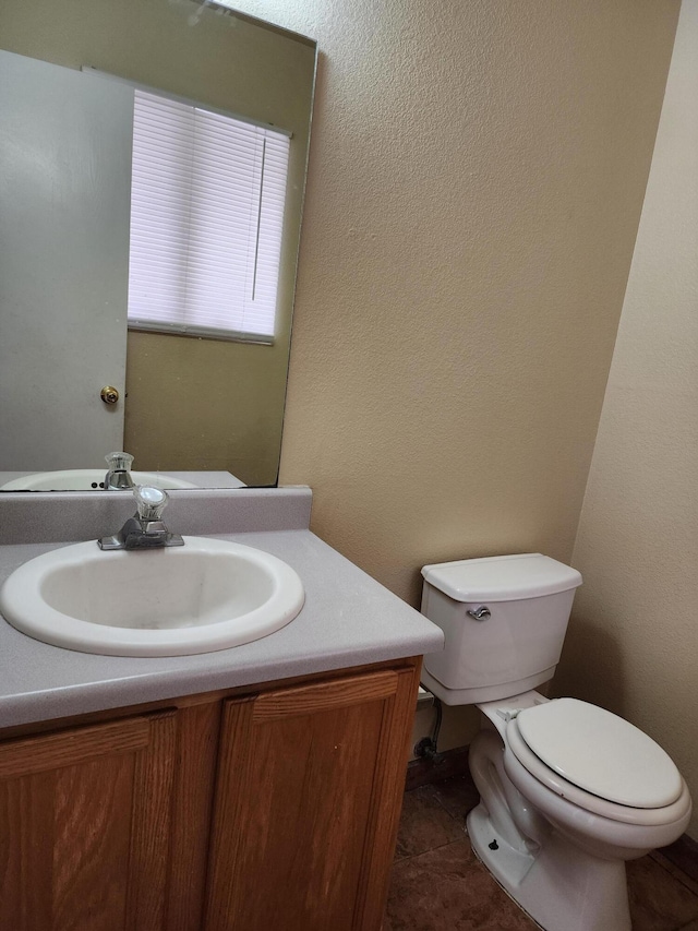 bathroom featuring vanity, toilet, and a textured wall