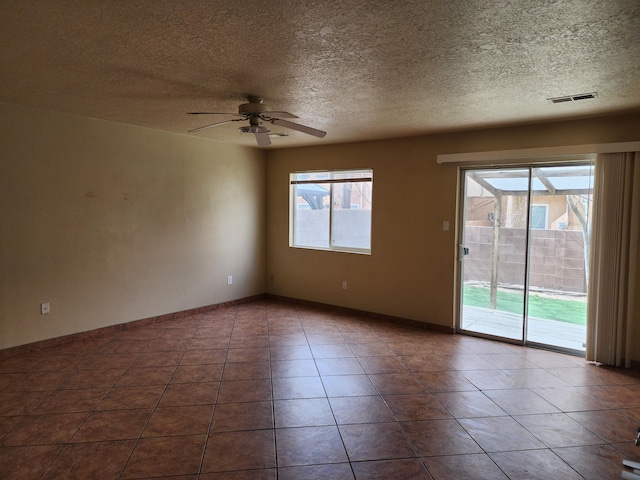 spare room with visible vents, dark tile patterned floors, a textured ceiling, baseboards, and ceiling fan