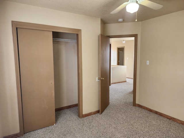 unfurnished bedroom with baseboards, ceiling fan, a closet, a textured ceiling, and light colored carpet