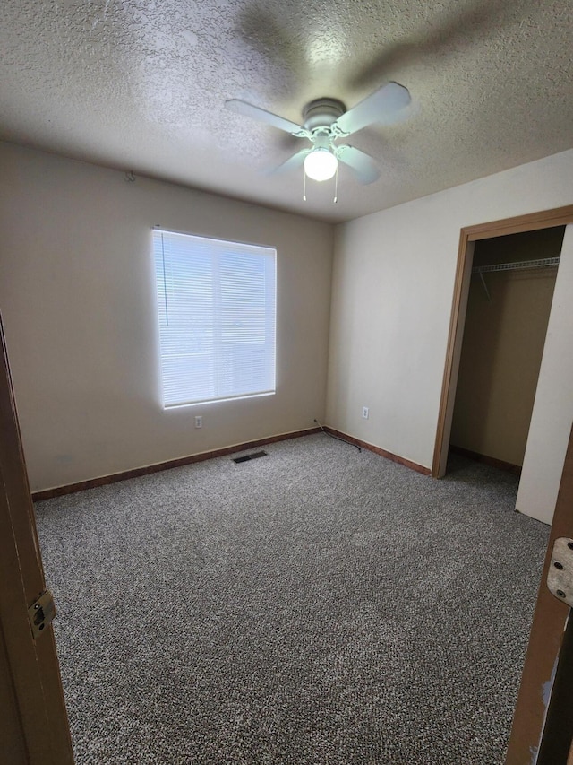 unfurnished bedroom with visible vents, baseboards, carpet, and a textured ceiling