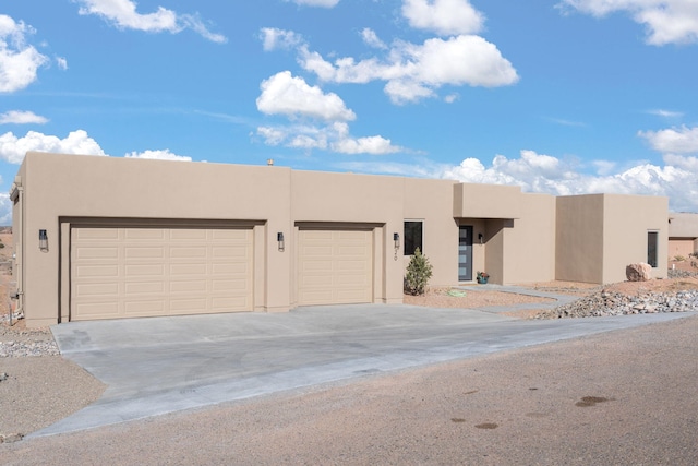 southwest-style home featuring concrete driveway, an attached garage, and stucco siding